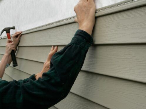 Workers installing siding on a house