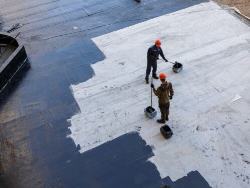 Waterproofing coating. A worker applies bitumen mastic to the foundation. Roofer cover the waterproofing primer on the roof, modified with polymer bitumen, with a roller brush.