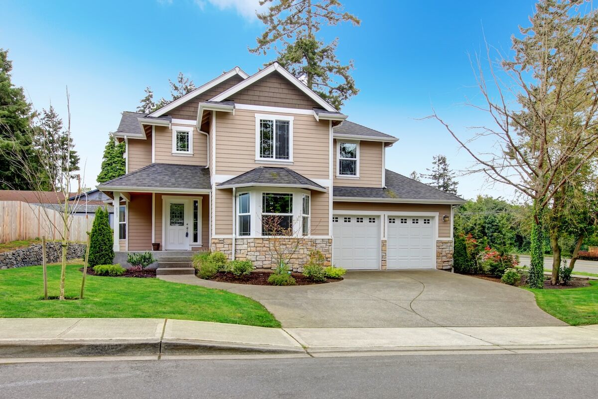 Tan vinyl house with tile roof, enclosed garage, and beautiful curb appeal