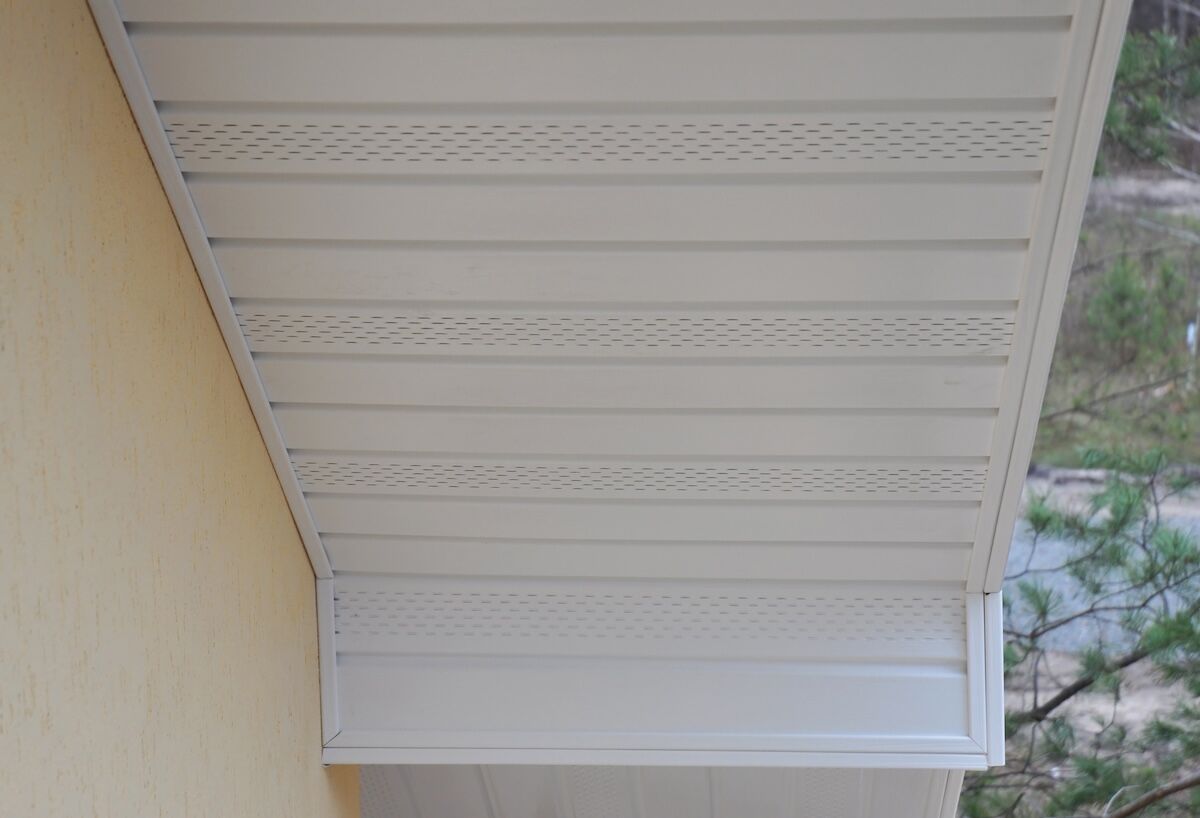 Plastic white uPVC soffit board below the facia of the roof with vents
