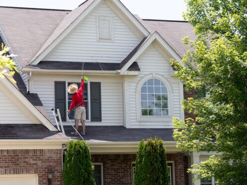 Homeowner washing the exterior of his house with a handheld sprayer