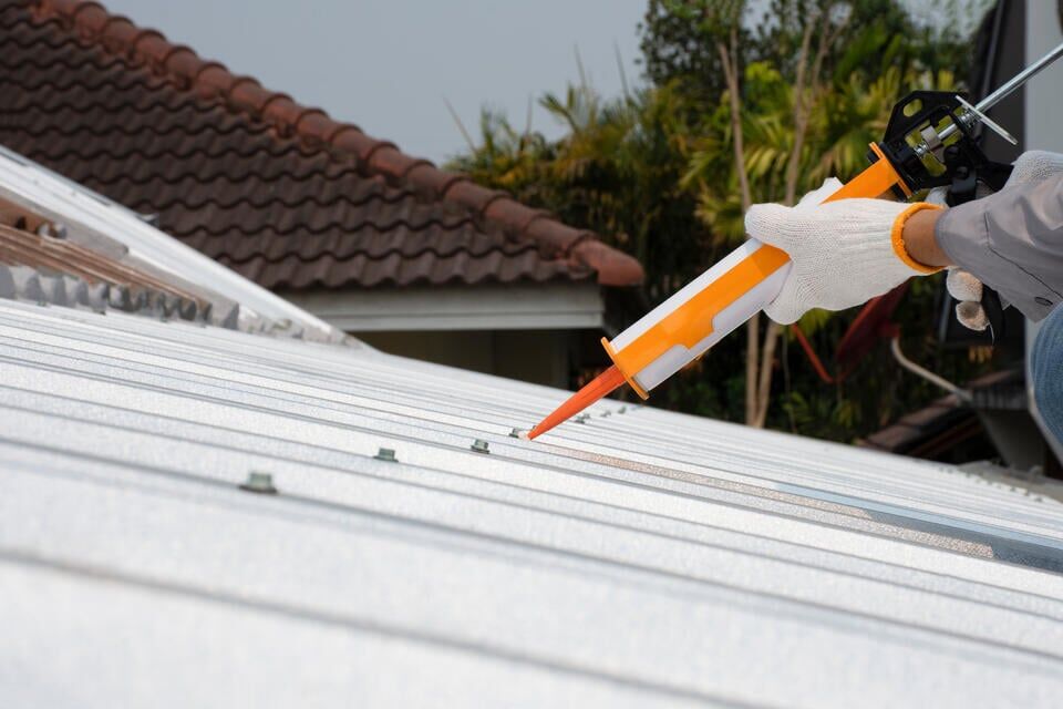 how to install metal roofing over shingles-roofer sealing sections of metal roofing