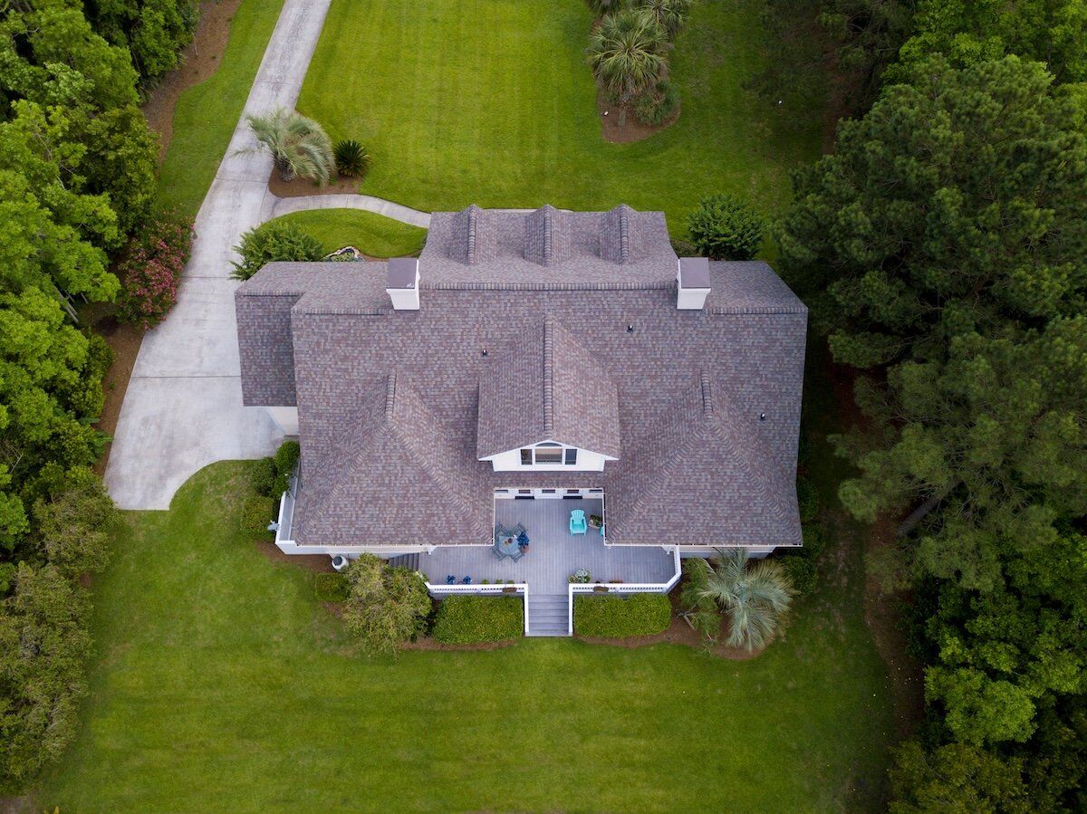 Aerial view of large home with new roof on beautiful property.