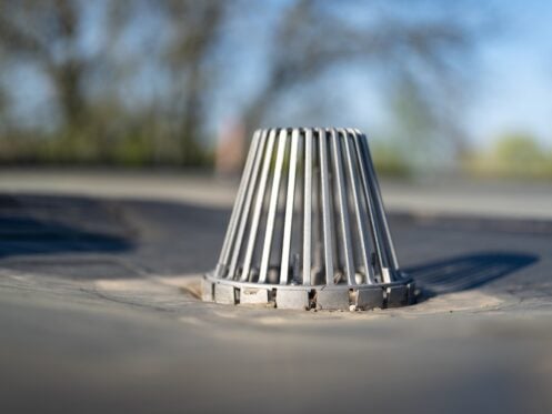 Clean metal caged roof drain on a flat EPDM roof.