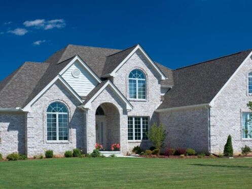 does a new roof increase home value-white brick house with new gray shingle roof