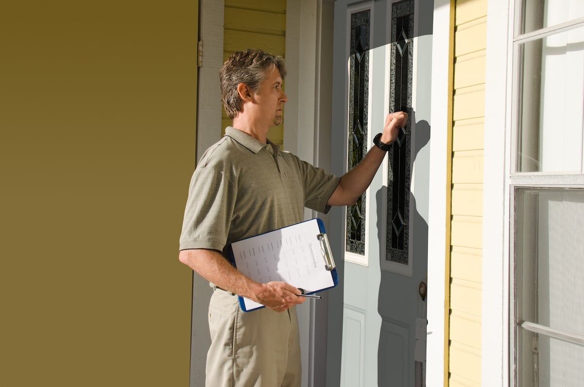 Man knocking on the front door of house doing door-to-door sales