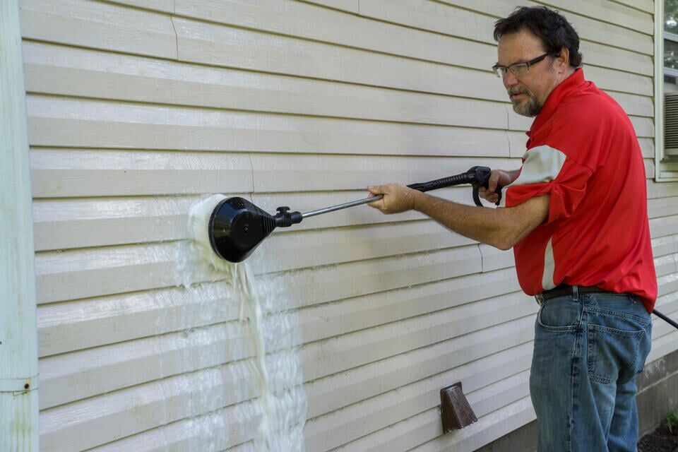 how to clean vinyl siding-man using a powered brush to scrub vinyl siding