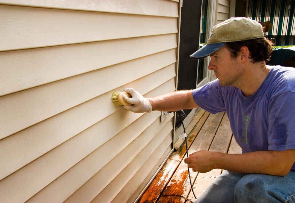 how to clean vinyl siding-man using a soft brush to scrub his vinyl siding