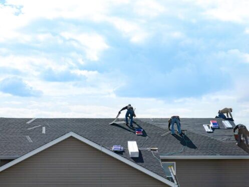 roof repair vs replacement-distant view of roofing crew replacing a house roof