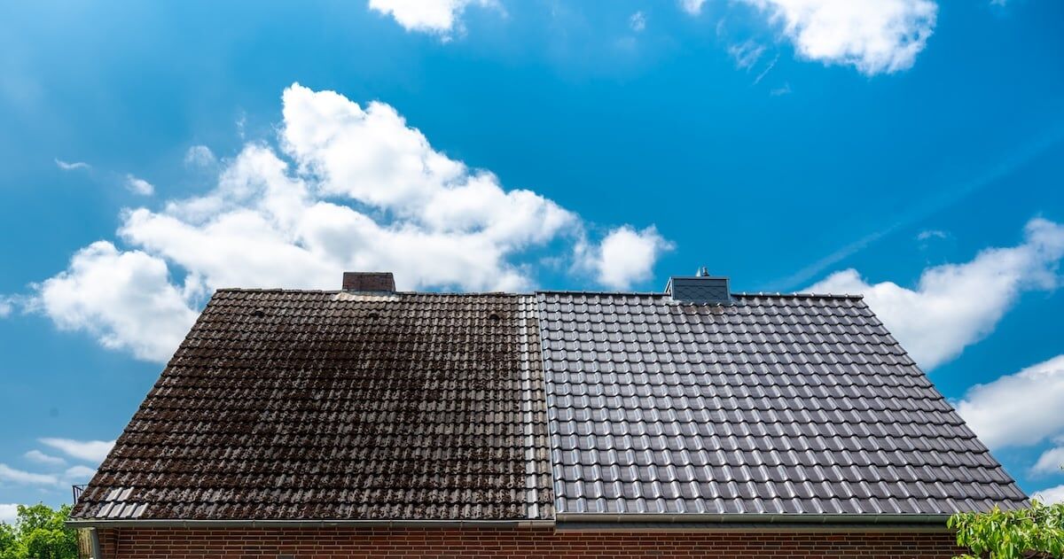 A half cleaned house roof shows the before and after effect of a roof cleaning.