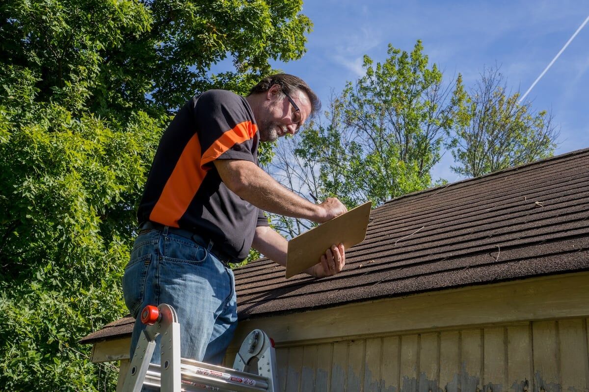 Contractor using a clipboard to figure out repair cost for storm damaged roof.