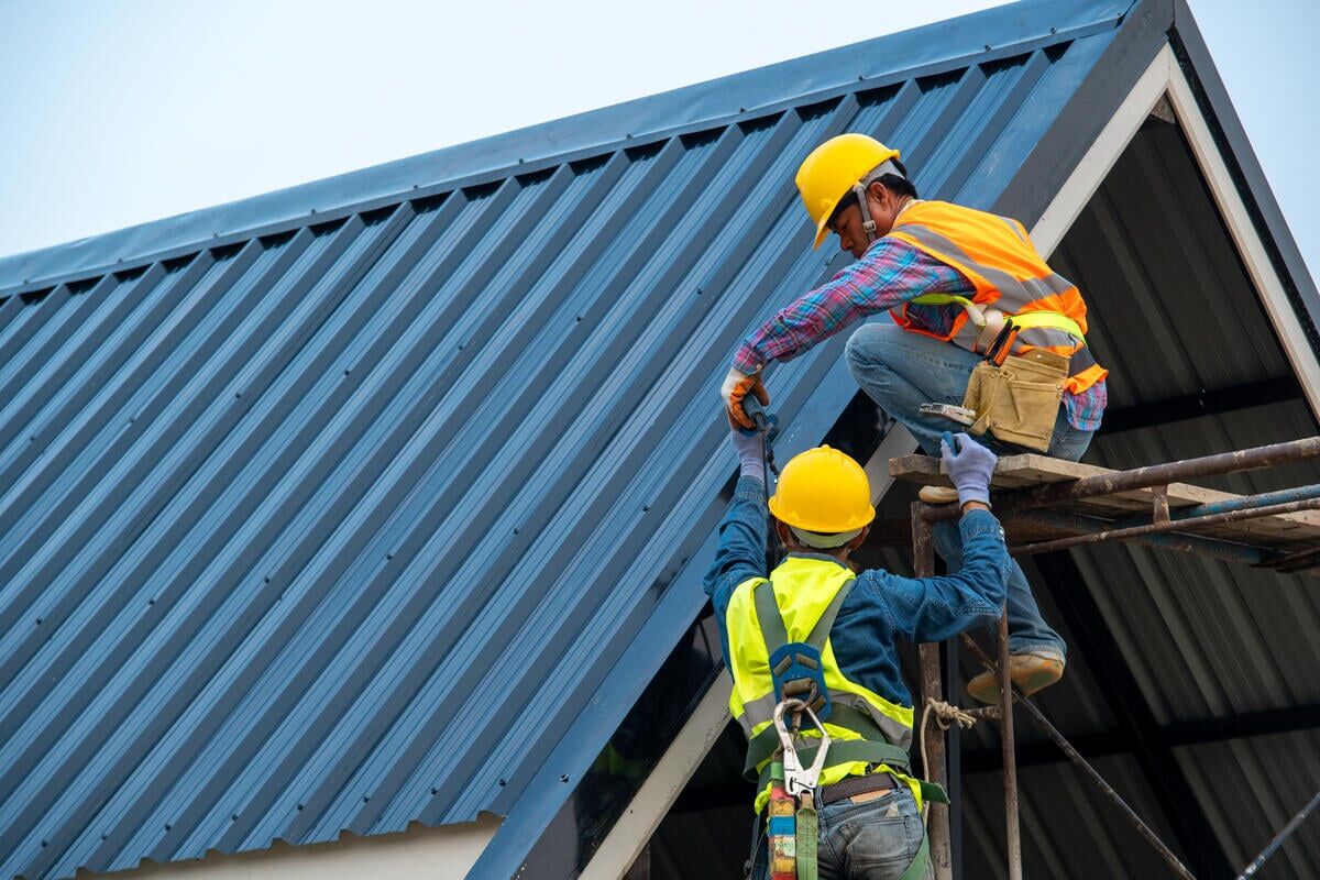 two roofers installing metal roofing