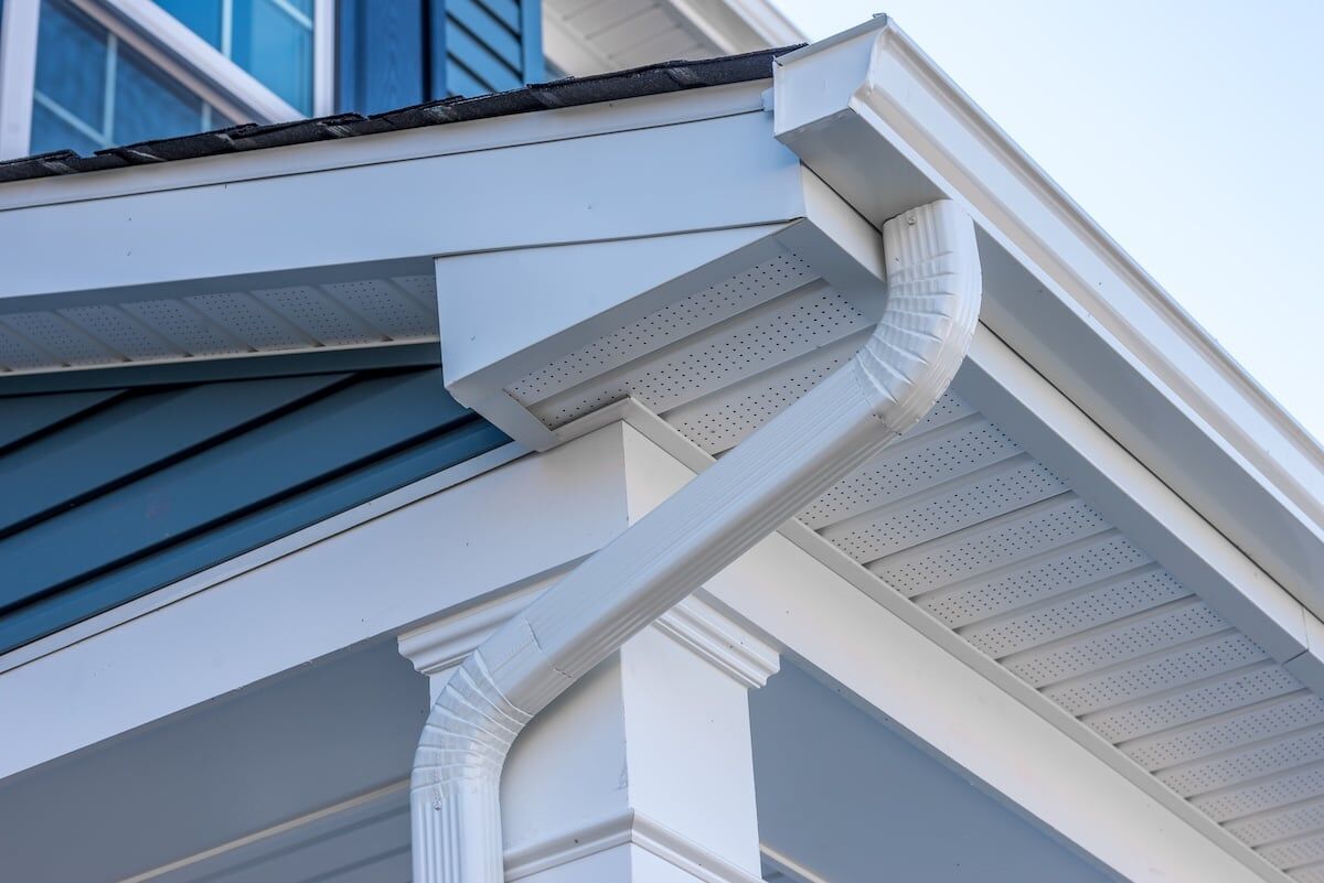 Colonial white gutter guard system, fascia, drip edge, soffit providing ventilation to the attic, with pacific blue vinyl horizontal siding at a luxury American single family home